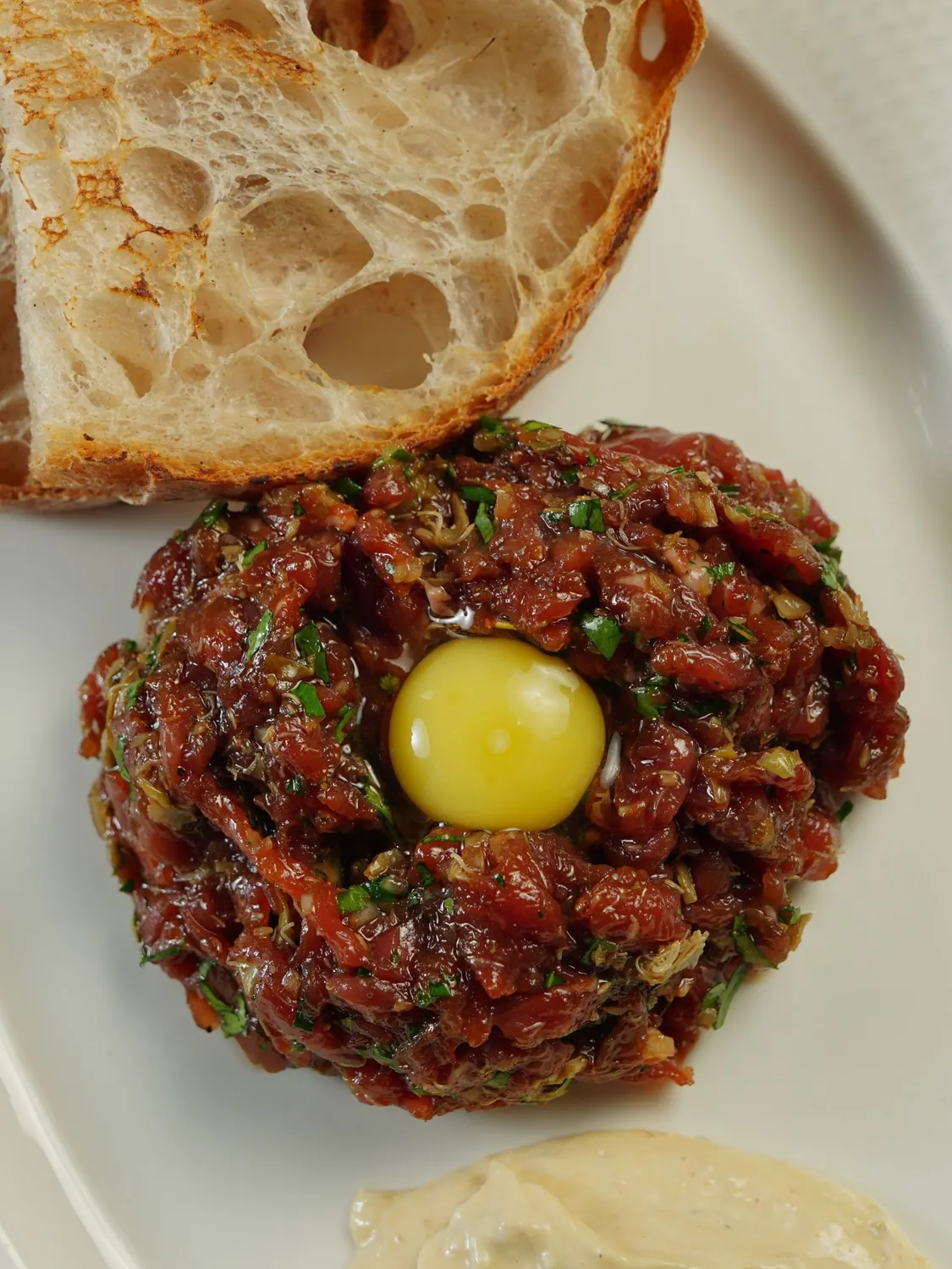 Tartare de bœuf surmonté d'un jaune d'œuf, avec du pain grillé